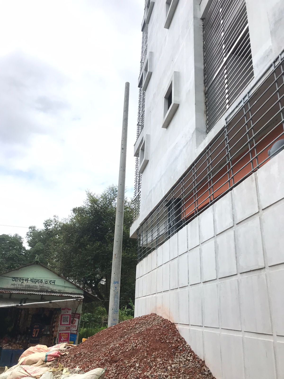 ভবনসংলগ্ন আরেকটি খুঁটি; পাশেই দোকানপাট।